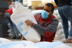 palestinian man carrying a bag of flour from UNRWA